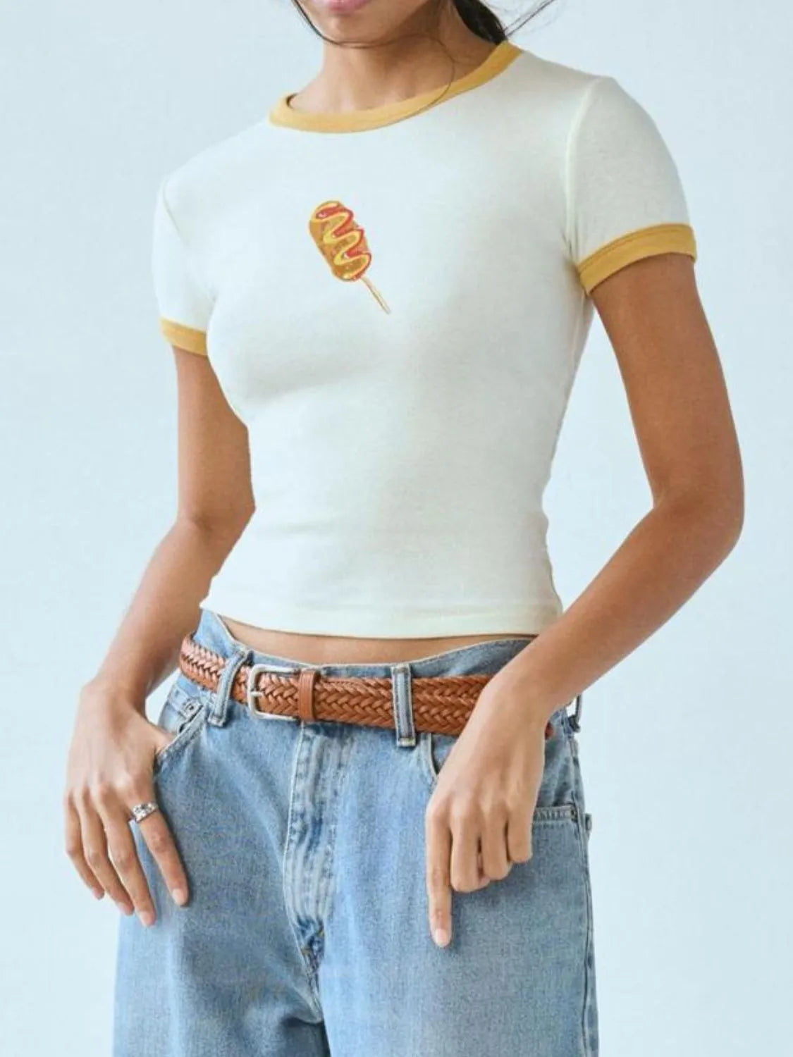 White and mustard yellow ringer baby tee featuring a printed corndog graphic on the chest.
