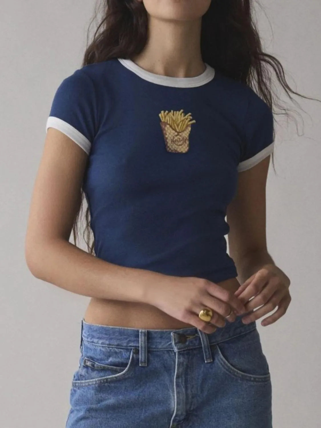 Blue baby tee with white trim and printed french fries cup graphic, styled with jeans.
