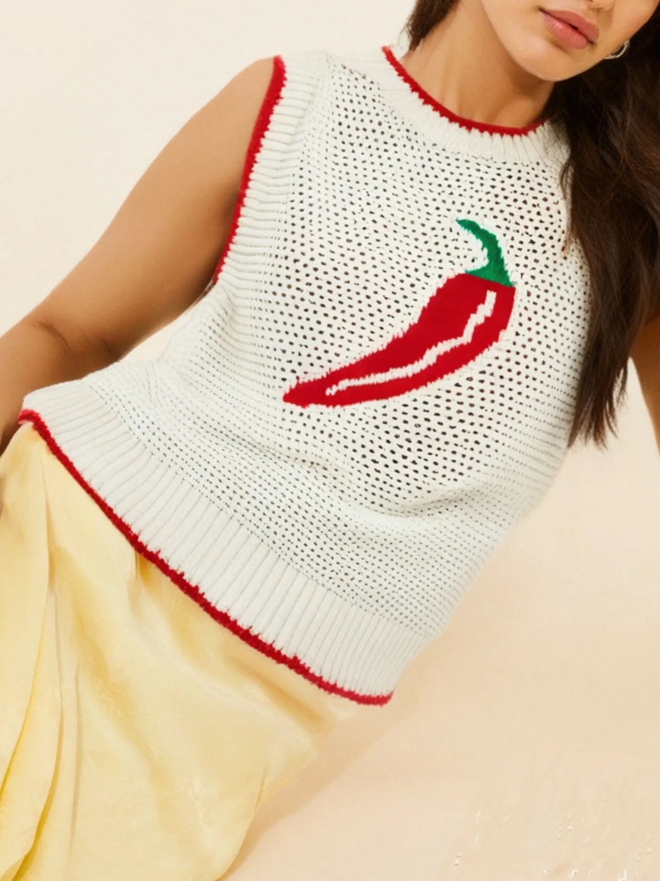 White sleeveless top with red chili pepper design on a beige background