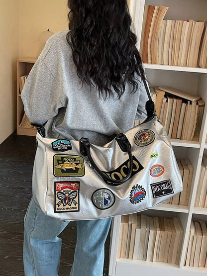 Person wearing a gray bag with patches in a room with bookshelves.