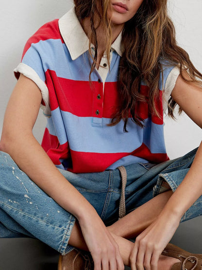 Person wearing a colorful striped polo shirt and jeans sitting on a chair.
