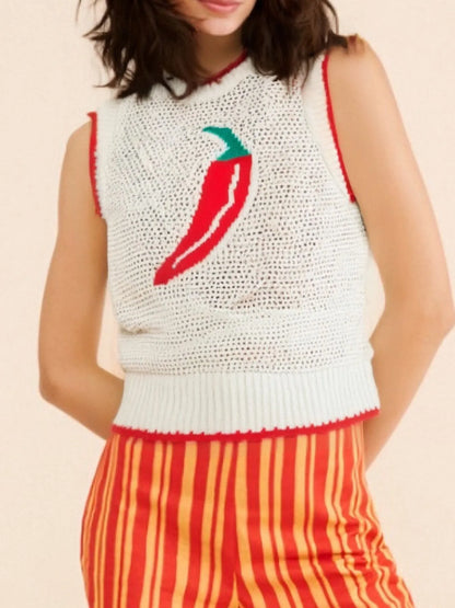 Person wearing a white sleeveless crochet top with a red chili pepper design and orange striped pants on a beige background.