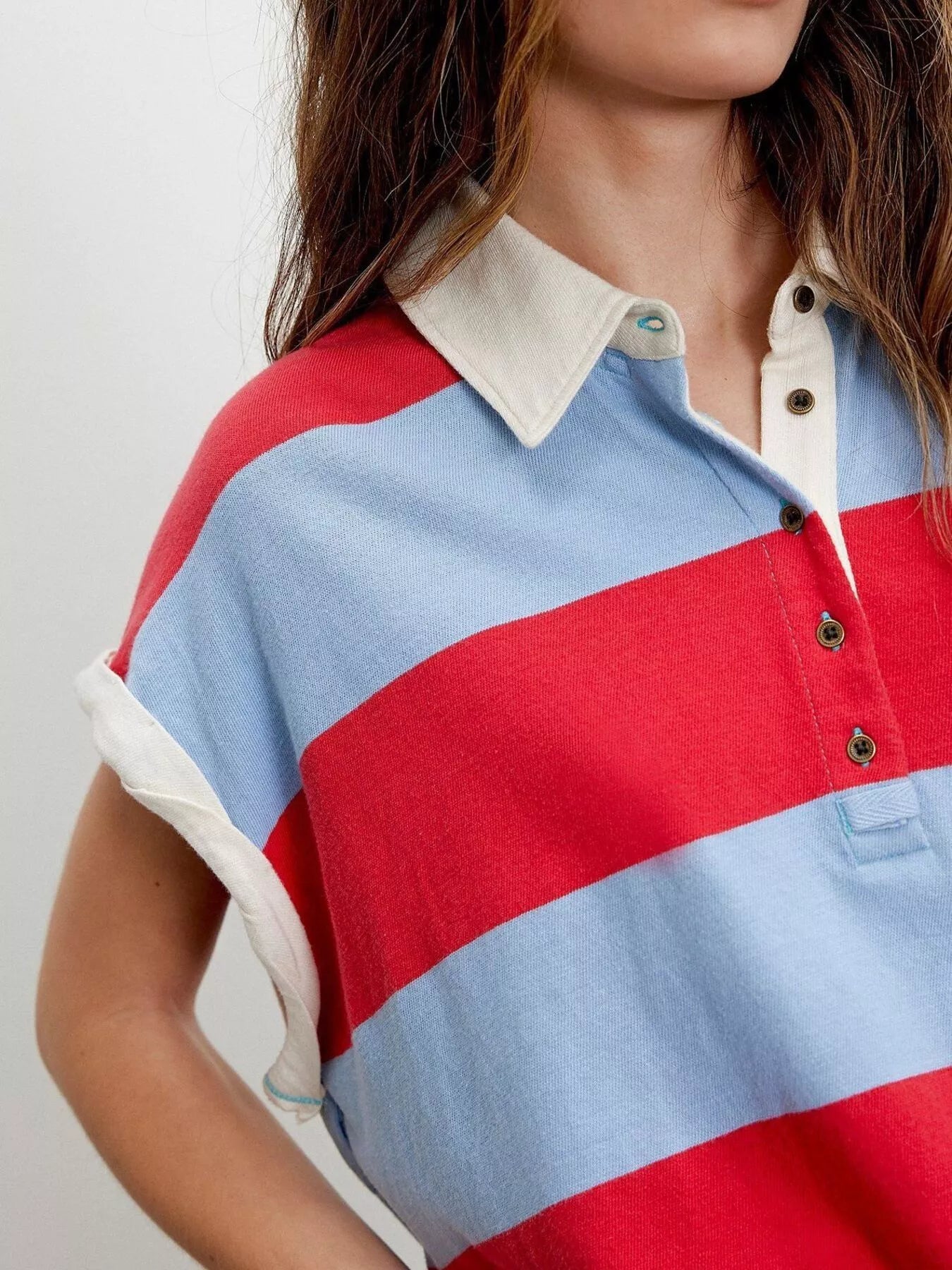 Close-up of a person wearing a red, blue, and white striped polo shirt.