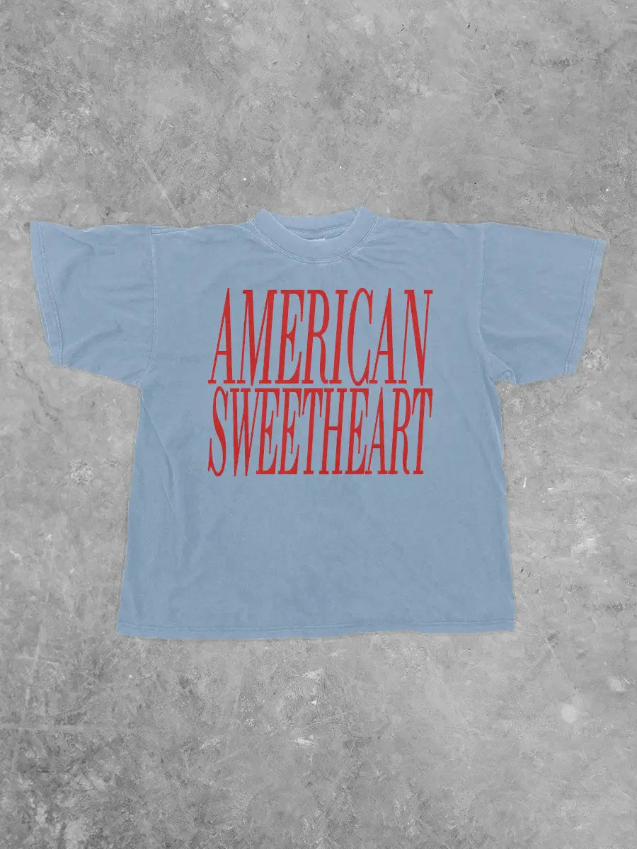 Light blue t-shirt with 'AMERICAN SWEETHEART' in red text on a gray concrete background
