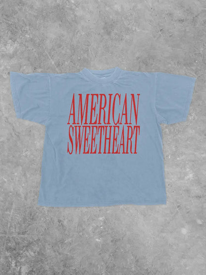 Light blue t-shirt with 'AMERICAN SWEETHEART' in red text on a gray concrete background