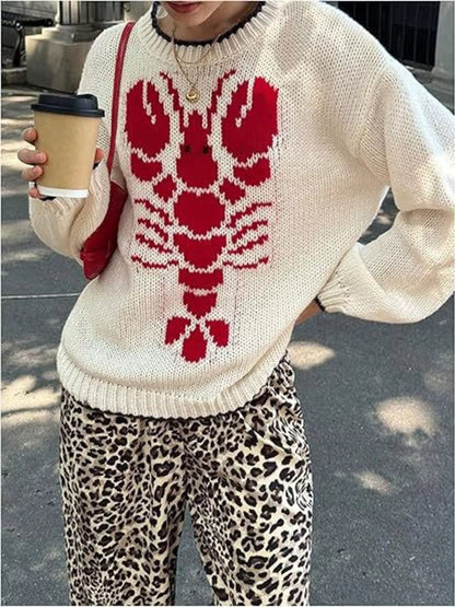 Person wearing a white sweater with a red lobster design, holding a coffee cup.
