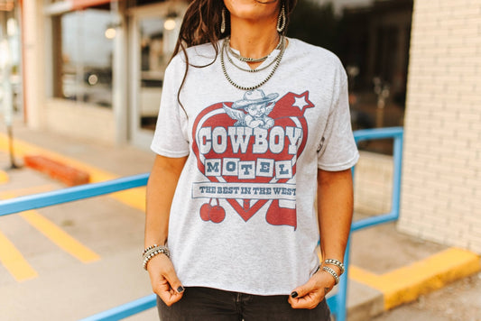 Person wearing a t-shirt with 'Cowboy Motel' design outdoors.