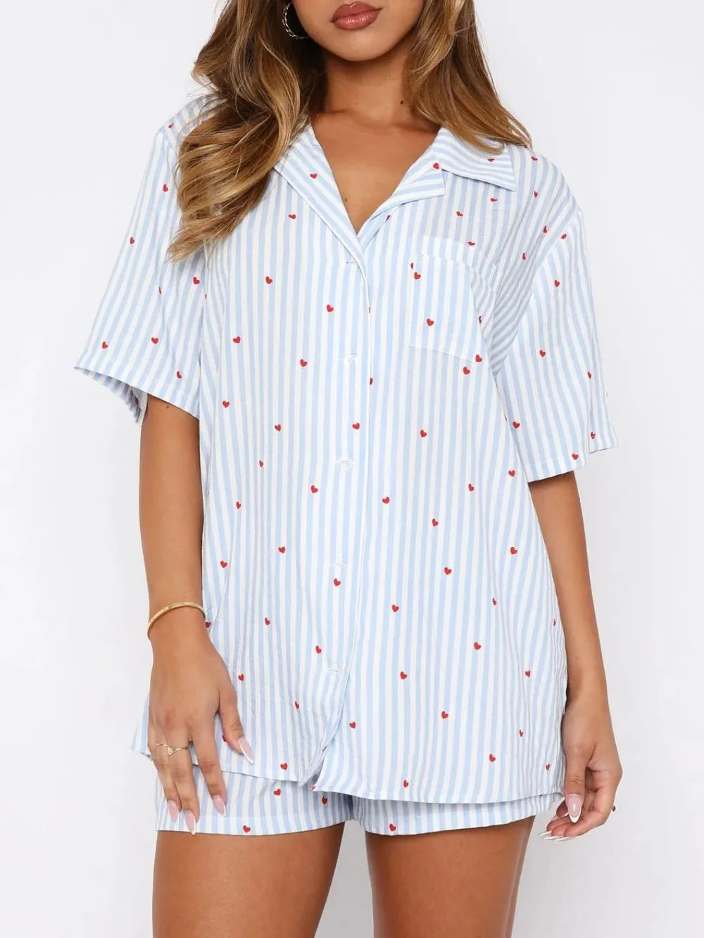Woman wearing a light blue striped pajama set with red hearts on a white background