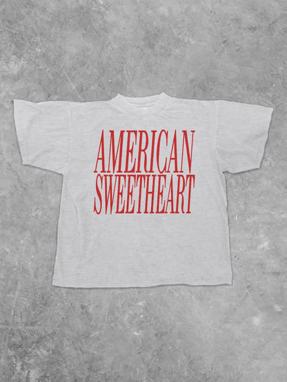 White t-shirt with 'AMERICAN SWEETHEART' in red text on a gray concrete background