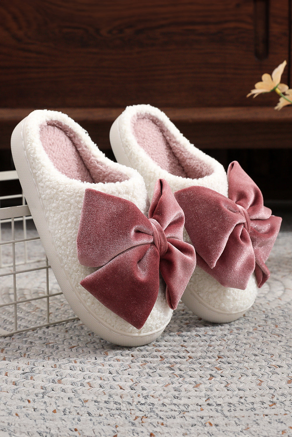 White slippers with pink bows on a textured surface