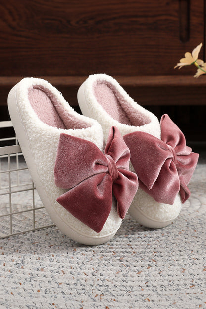White slippers with pink bows on a textured surface