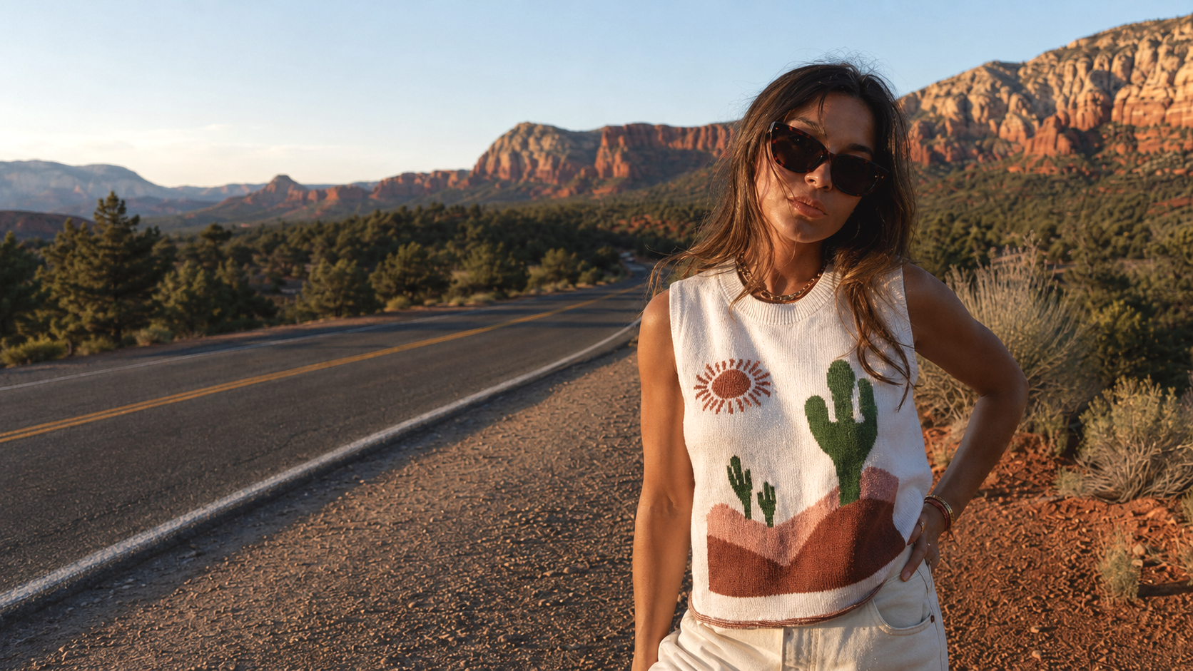 Woman standing on a road with desert landscape and mountains in the background