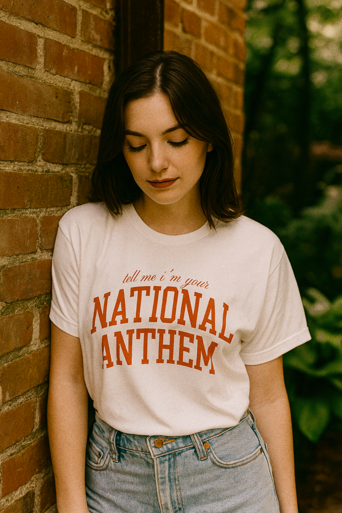 Girl wearing "Tell Me I'm Your National Anthem" tee at outside a truck stop in vintage Americana aesthetic