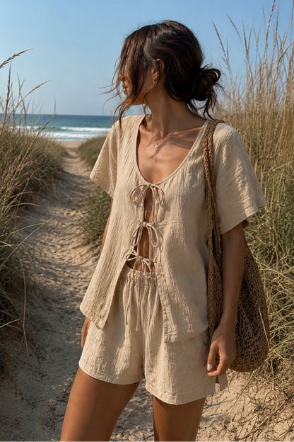 Woman walking on a sandy path with ocean view wearing a beige outfit.